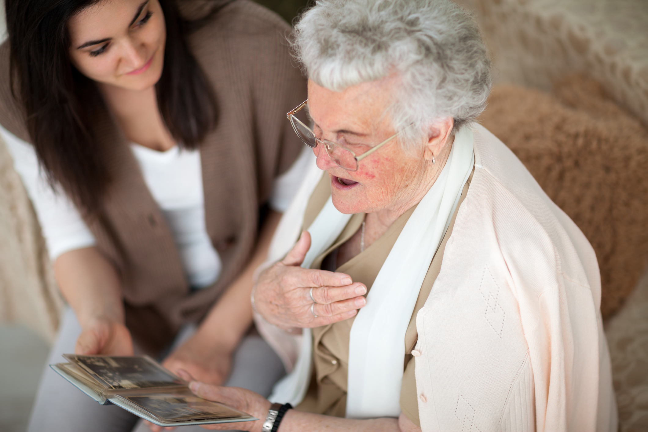 Photo of grandmother looking at photo and telling a story while granddaughter listens